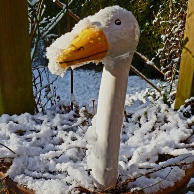 Bild vergr&ouml;&szlig;ern: Eine wei&szlig;e Gans aus Holz steht im Schnee, symbolisch f&uuml;r den Winter.