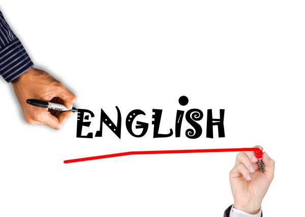Bild vergr&ouml;&szlig;ern: Eine minimalistische Komposition auf rein wei&szlig;em Untergrund. Im linken Bereich ist die Hand eines Mannes in einem gestreiften Hemd zu sehen, die mit einem schwarzen Permanentmarker das englische Wort &raquo;ENGLISH&laquo; schreibt. Die Buchstaben sind in einem verspielten, unregelm&auml;&szlig;igen Serifenschrift-Stil gezeichnet. Unten rechts setzt eine zweite Hand (mit lackierten Fingern&auml;geln) an, um das geschriebene Wort mit einem roten Filzstift von rechts nach links mit einer klaren, roten Linie zu unterstreichen.