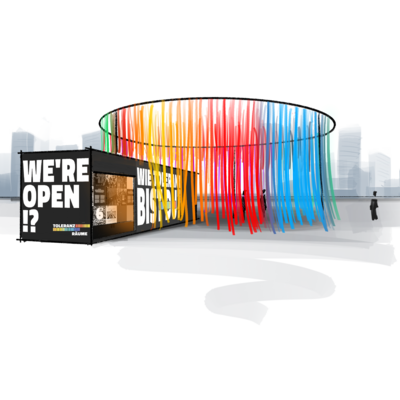 Ein schwarzer Ausstellungs-Container steht im Freien. Darauf steht in wei&szlig;er Schrift WE'RE OPEN!? und WIE TOLERANT BIST DU?. Daneben h&auml;ngt ein gro&szlig;er, runder Vorhang aus vielen bunten B&auml;ndern in Regenbogen-Farben.