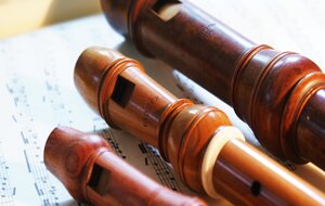 Drei Blockfl&ouml;ten aus Holz liegen auf Notenpapier. Zu sehen sind die Mundst&uuml;cke der Instrumente im Detail. Das Holz hat unterschiedliche Braunt&ouml;ne.